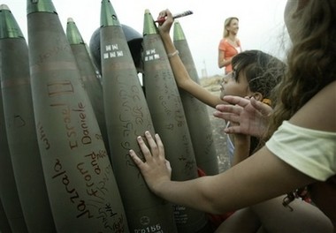'Israeli girls write messages on a shell at a heavy artillery position near Kiryat Shmona, in northern Israel'