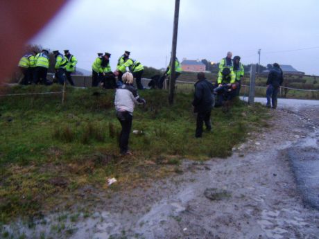 Protesters are flung across a barbed wire fence into a low lying field.