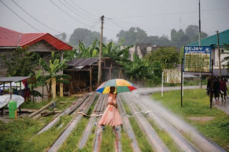 a woman walks across a dangerous pipeline network in the Niger Delta